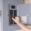 Hand adjusting a circuit breaker in an electrical panel, ensuring home safety and efficiency.